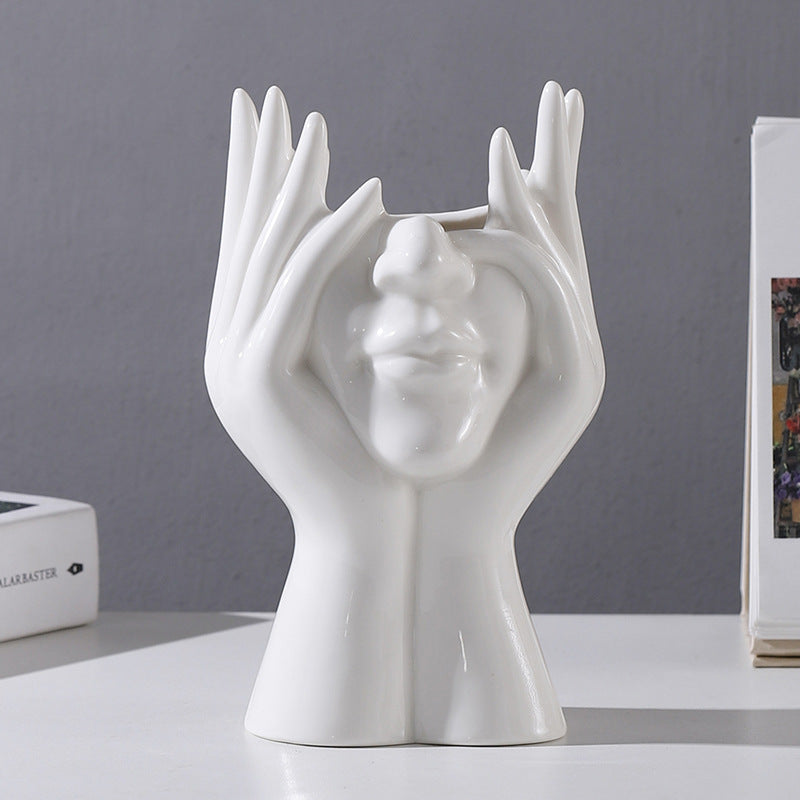 White ceramic sculpture of hands cradling a face, modern home decor accent piece