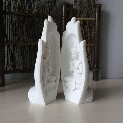 White Buddha statues in hand-shaped frames for modern home decor